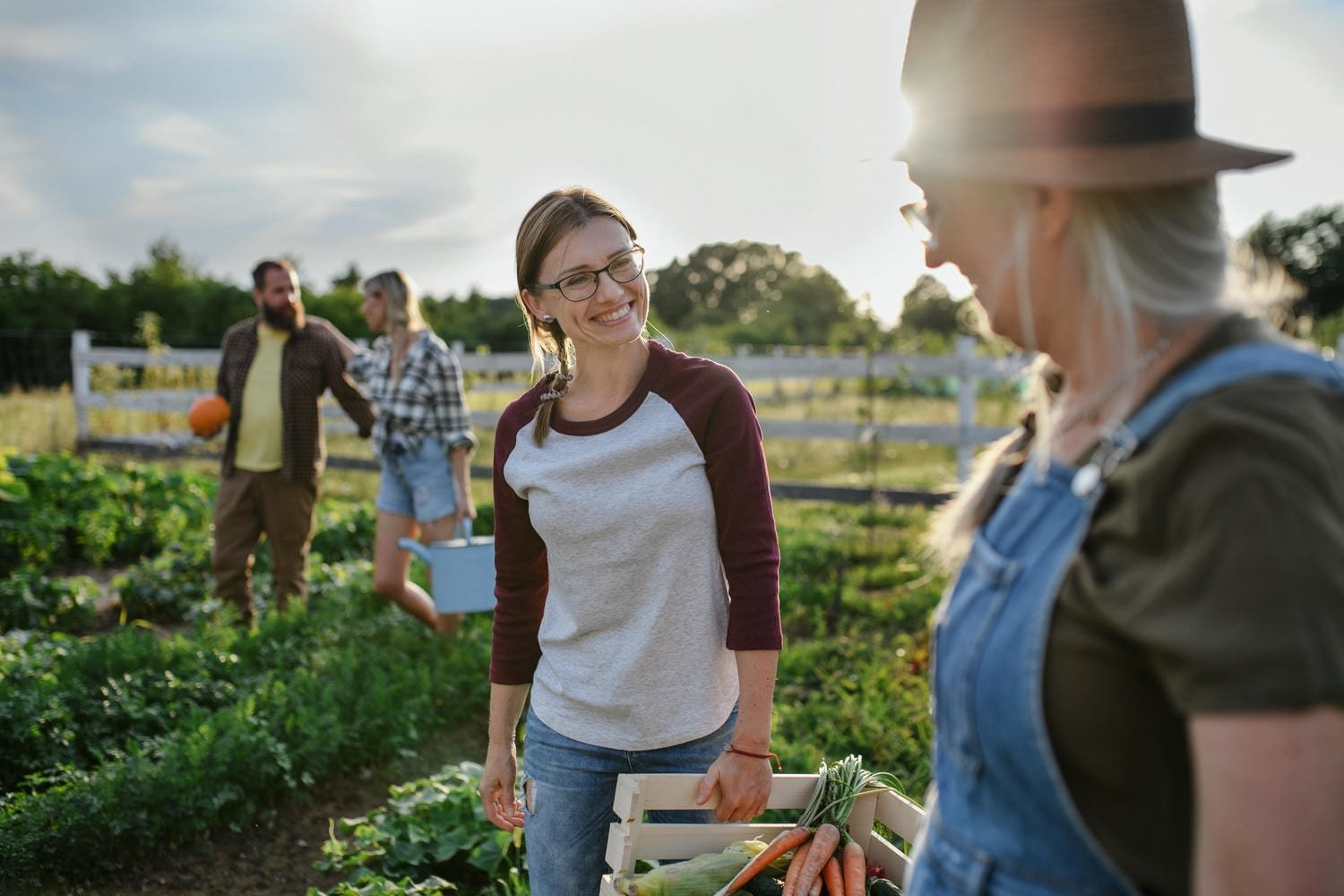 Two gardeners carrying a crate of fresh produce on a farm